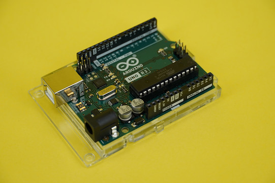 Nahaufnahme des Arduino Uno Microcontrollers auf gelbem Hintergrund