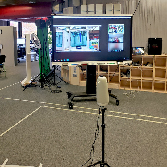 Setting mit einer freistehenden Owl im Raum E1, im Hintergrund ein Smartboard mit der Zoomkonferenz