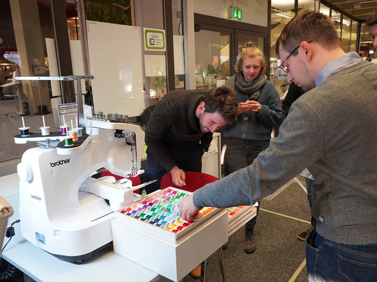 Gruppe von Studierenden erkundet die Stickmaschine