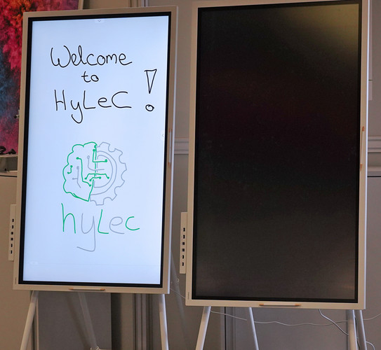 Zwei Flipcharts im Raum E1, auf dem Linken wurde per Hand geschrieben, das Rechte ist ausgeschaltet