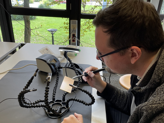 Ein Mitarbeiter bei der Lötarbeit. Er nutzt die Ersa Lötstation und einen Platinenhalter