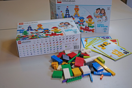 2 Lego-Konstruktionsboxen, davor etwas Lego zerstreut und Beispielkarten mit Bauanleitung