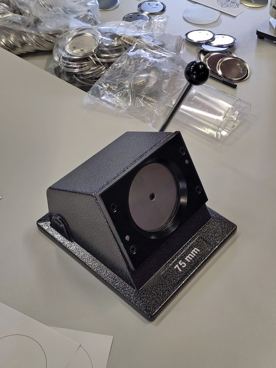Papierstanze auf einem Tisch mit Zubehör der Buttonmschine drumherum