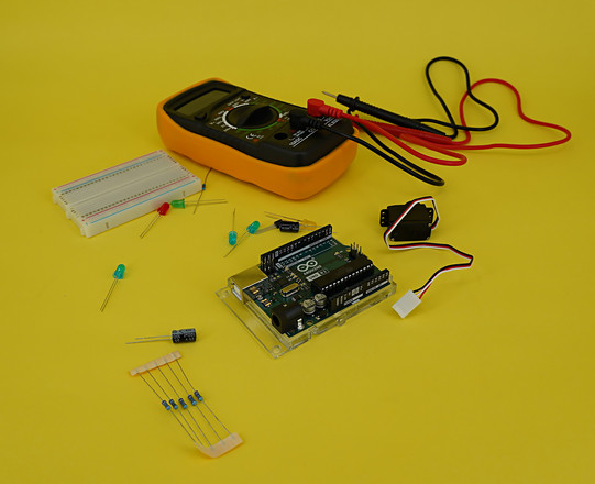 Nahaufnahme des Arduino Uno Microcontrollers auf gelbem Hintergrund mit Zubehör