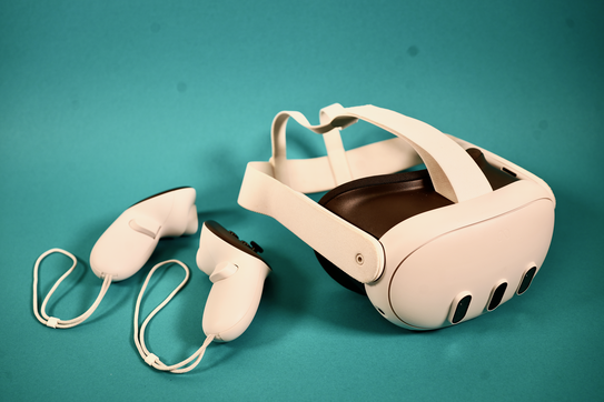 Produktfoto der Meta Quest 3-Brille. Links daneben liegen die beiden Controller für die Handsteuerung.